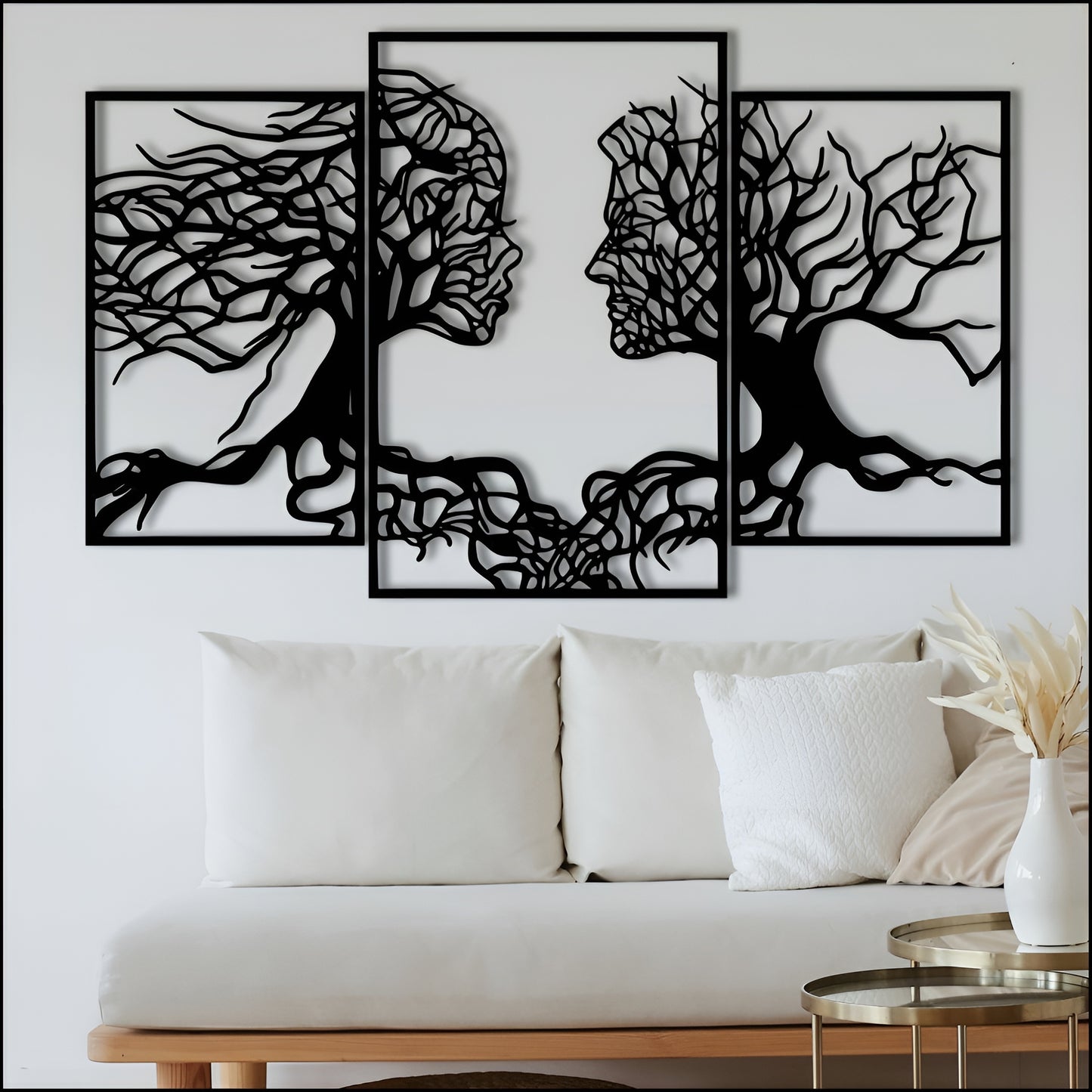 Three black abstract wall art pieces on a white wall above a white sofa.