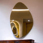 Gold oval mirror on a white wall with a wooden cabinet below