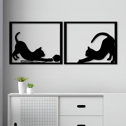 Two black framed wall art pieces of cats on a gray wall above a white cabinet.