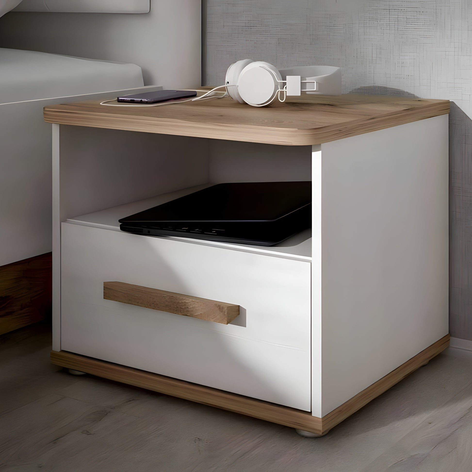 White nightstand with wooden top and legs, featuring a laptop and phone on top.
