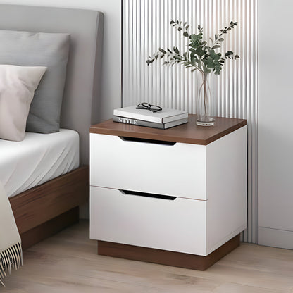 White nightstand with wooden top next to a bed with gray and white pillows.