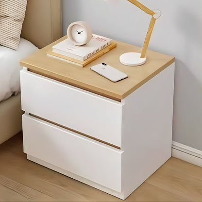 White nightstand with wooden top featuring a lamp, phone, and books in a bedroom setting.