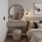 Modern bedroom with round mirror, vanity table, and bed.