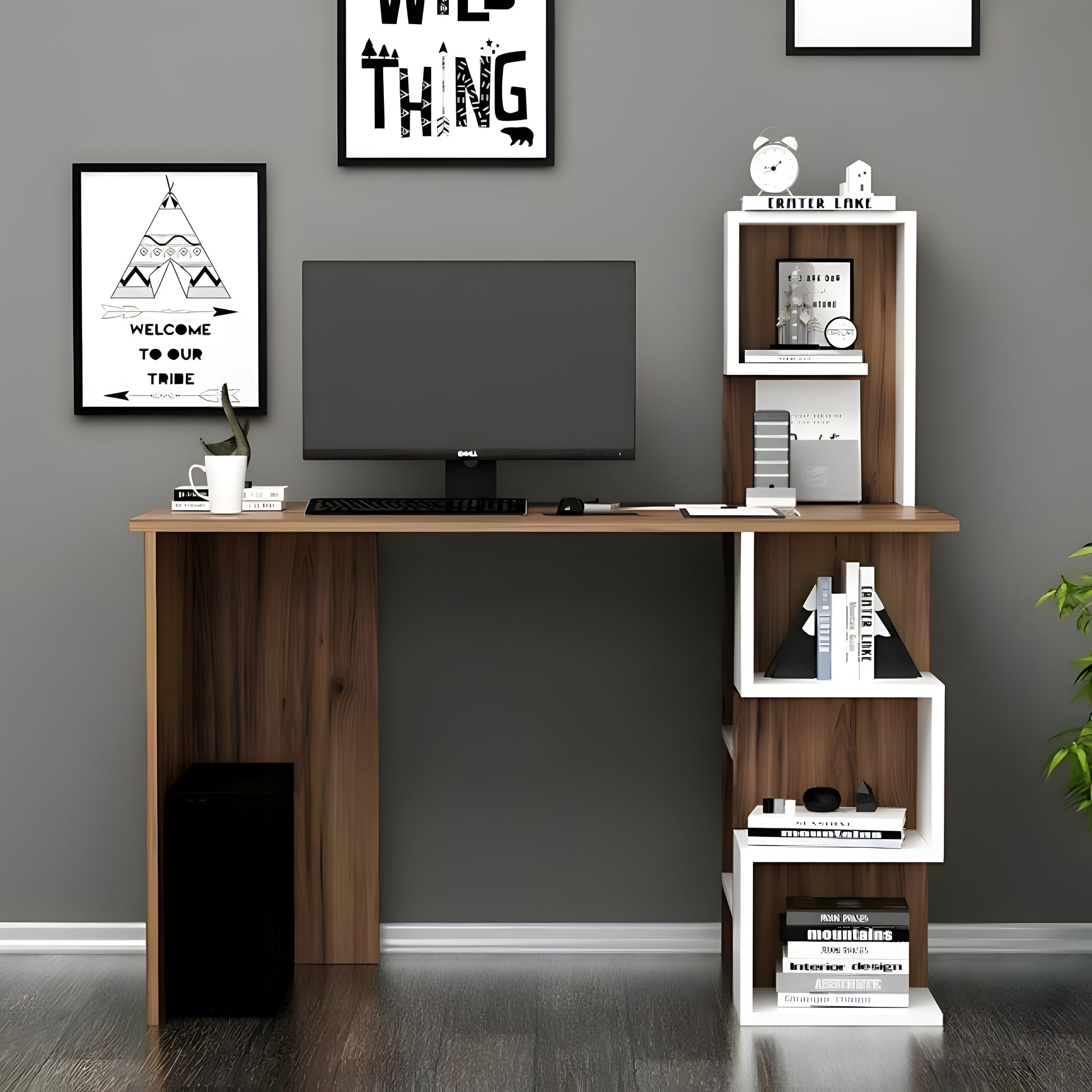 Wooden desk with a computer setup against a gray wall with framed artwork.