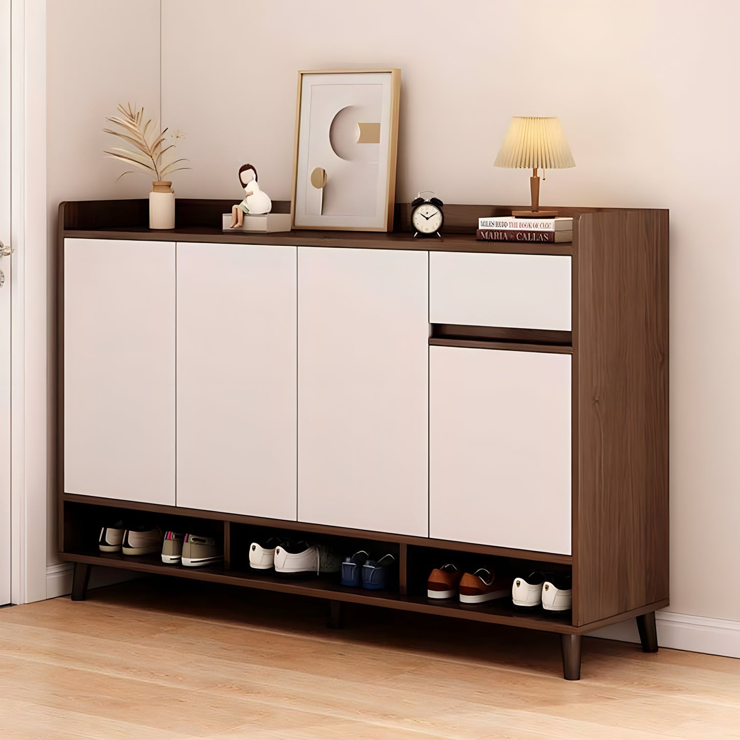 Wooden shoe cabinet with white doors and shoes inside, against a light wall.