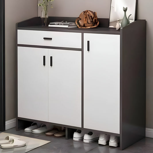 White shoe cabinet with black top and sides, shoes underneath, on a gray floor.