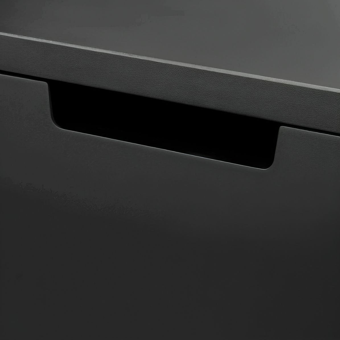 Close-up of a black drawer with a metallic handle on a dark gray background