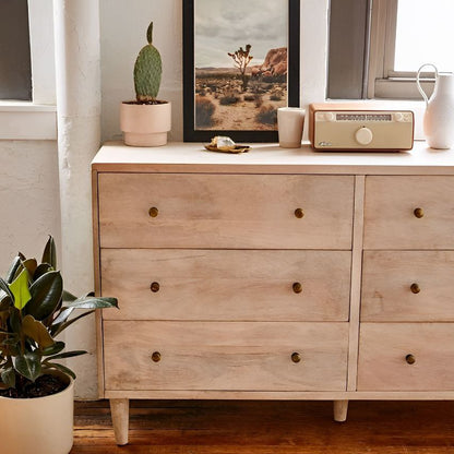 Wooden dresser with decorative items in a room with a rug and plant