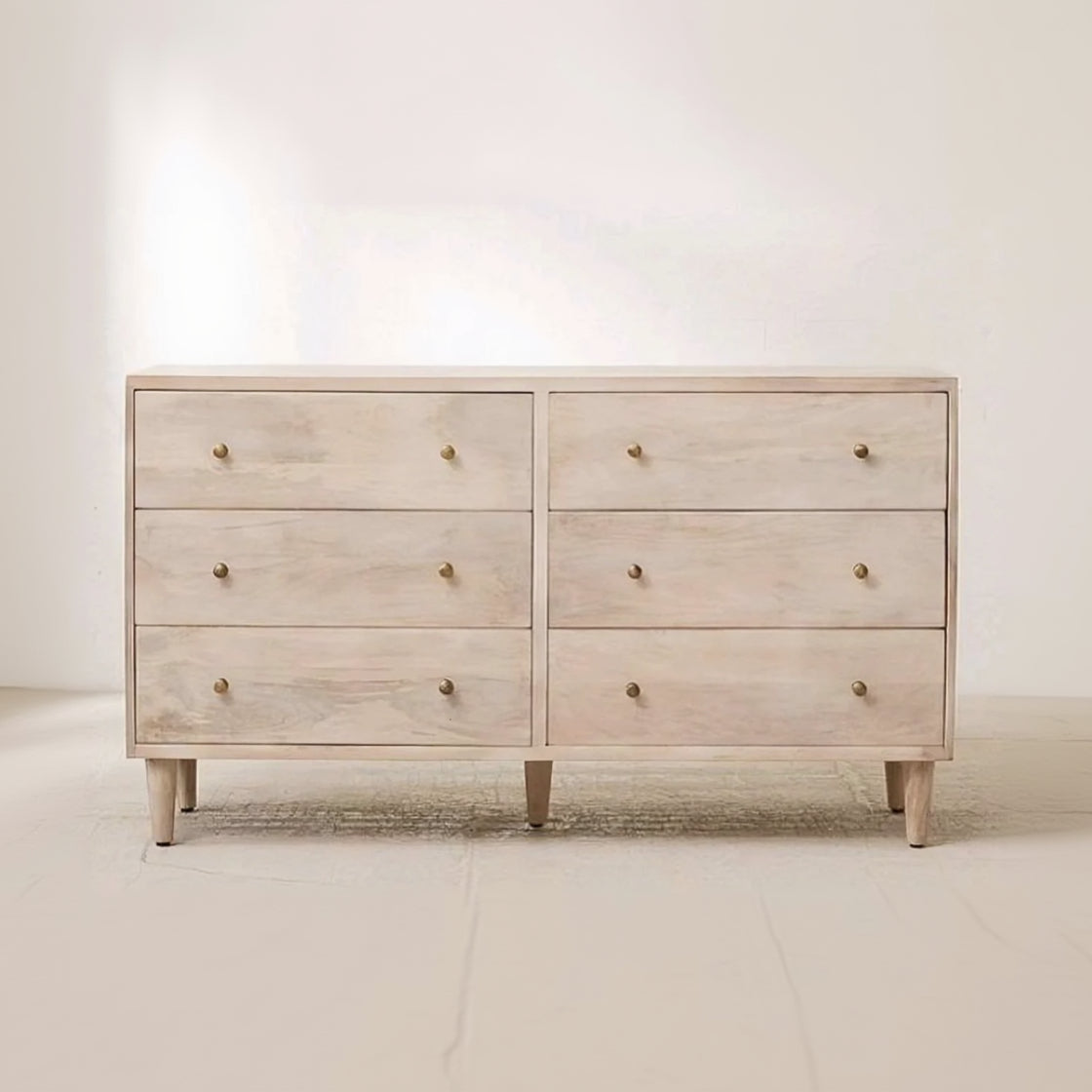 Light wooden dresser with six drawers on a plain background