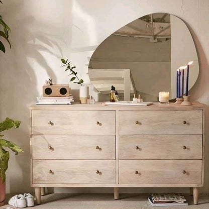 Wooden dresser with round mirror in a bedroom setting