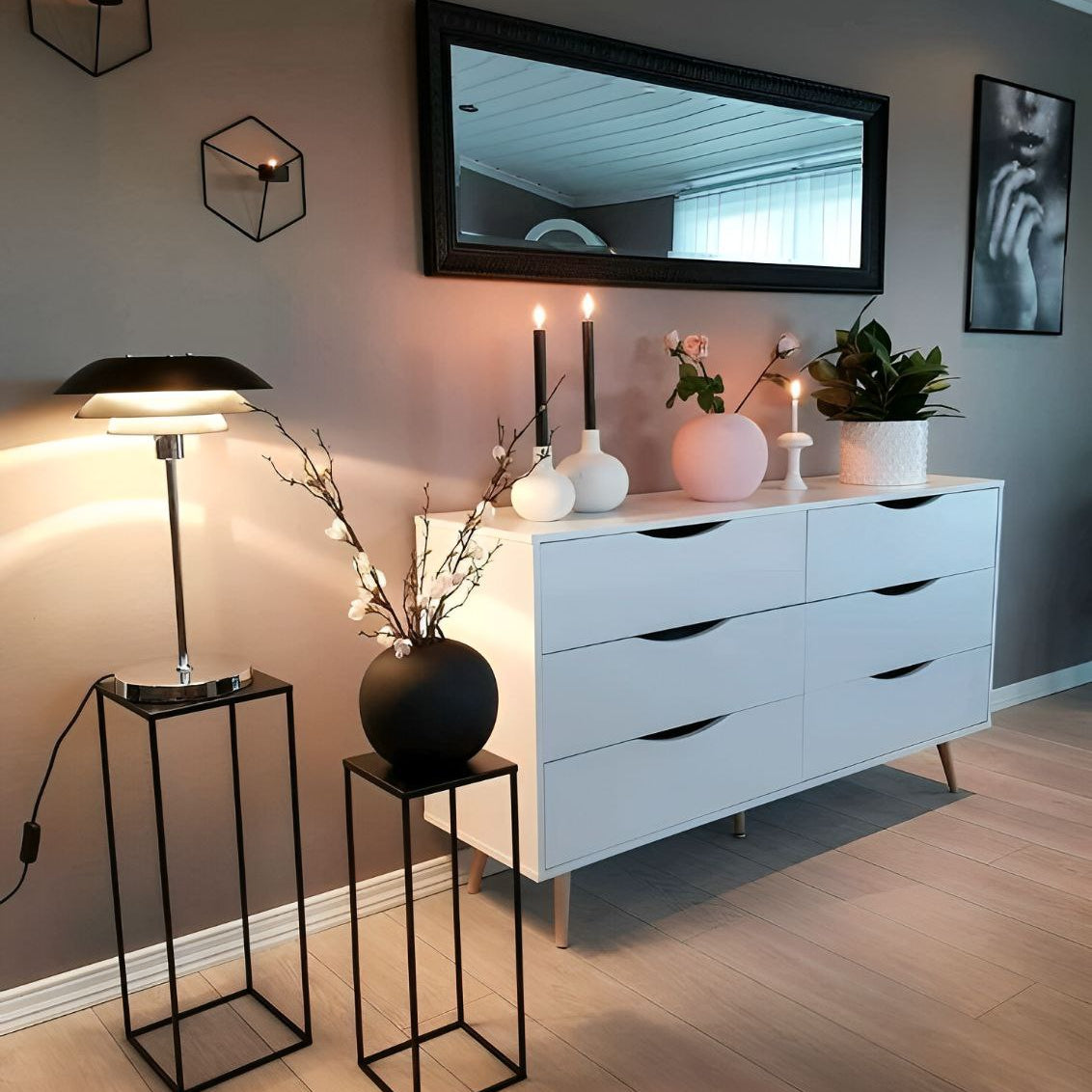 Modern bedroom with white dresser, decorative items, and a lamp.
