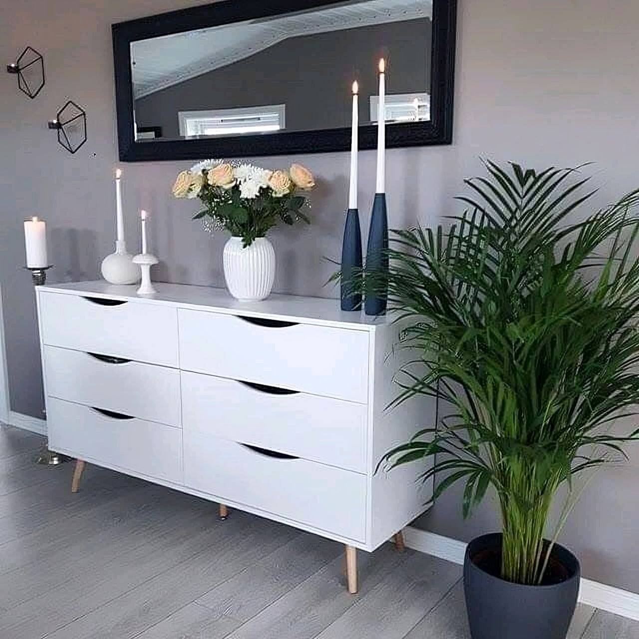 White dresser with decorative items including candles and a plant in a room.