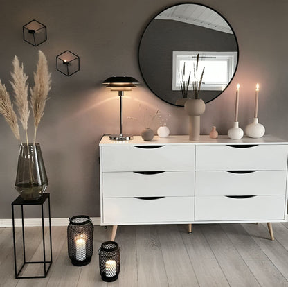 Modern interior with a white dresser, decorative items, and a round mirror.