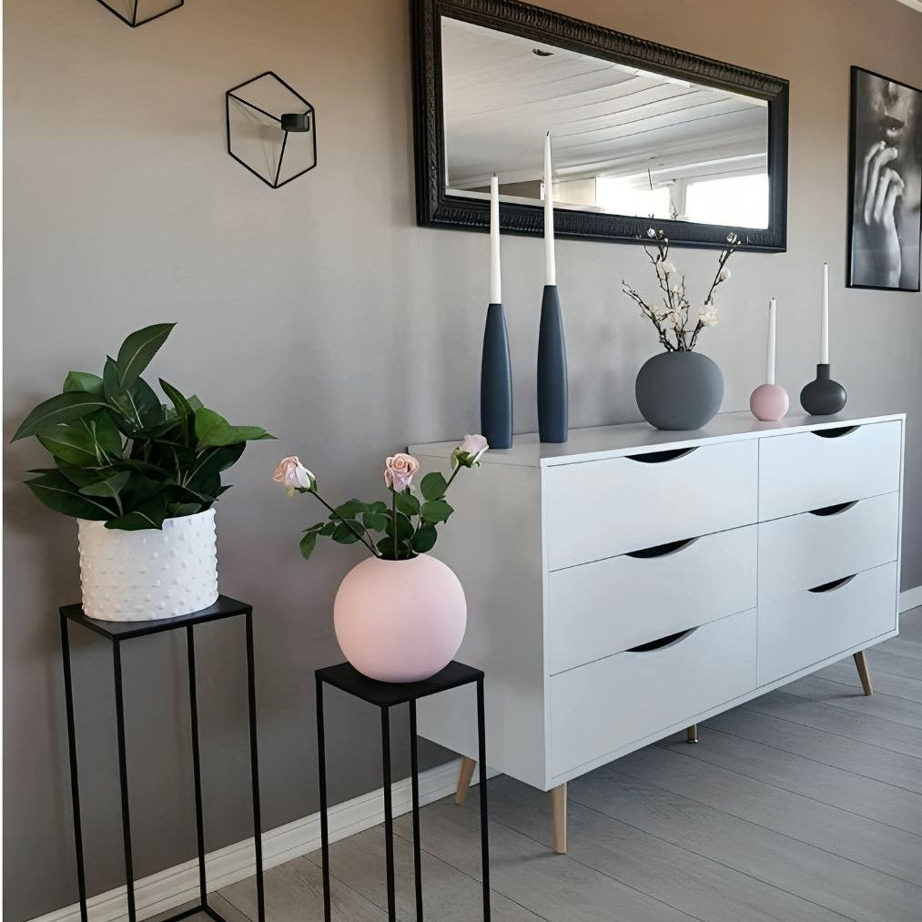 Modern interior with white dresser, decorative vases, and plants against a gray wall.