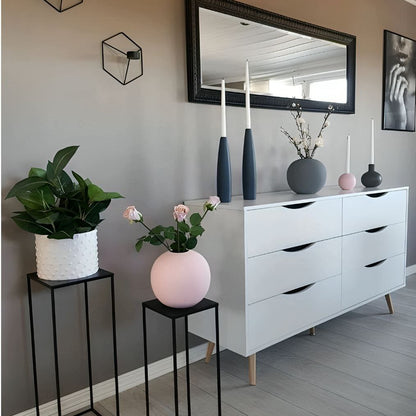 Modern interior with white dresser, decorative vases, and plants against a gray wall.