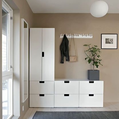 Modern interior with white storage unit, coat rack, and plant in a room with large window.