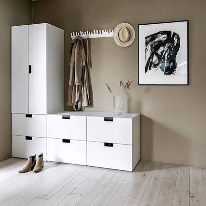 Modern interior with white storage unit, coat rack, and abstract art on a beige wall.