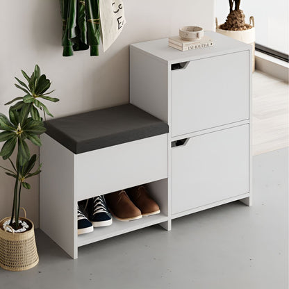White shoe storage bench with gray cushion and two drawers, featuring shoes and a plant in a minimalistic setting.