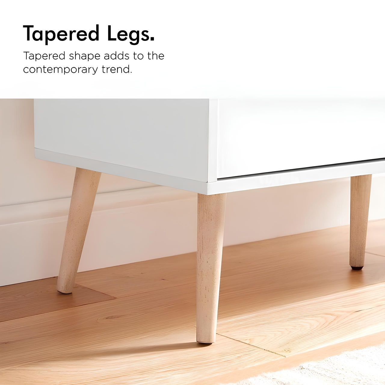 Close-up of a table with tapered legs on a wooden floor.