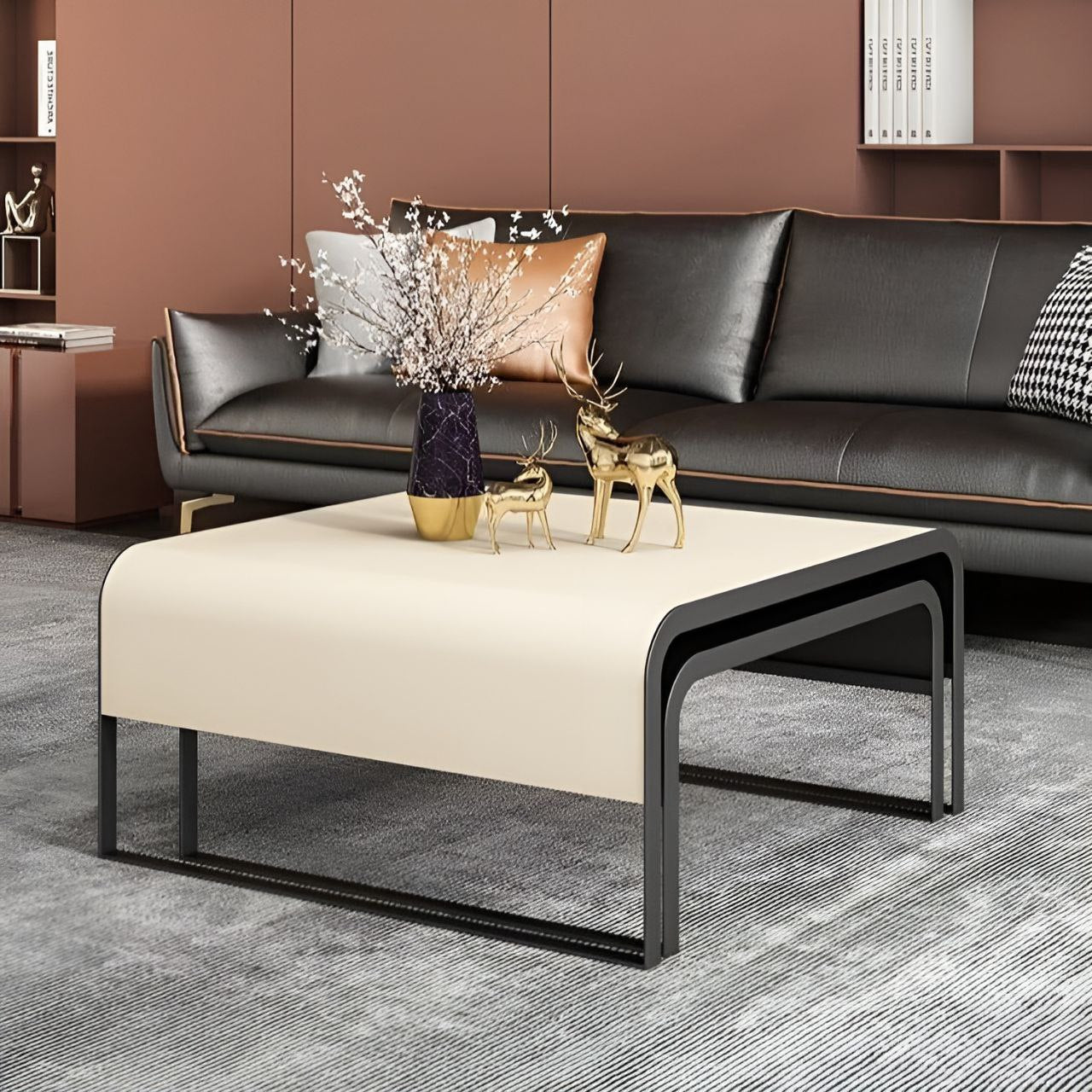 Modern living room with a black sofa, beige ottoman, and decorative items.